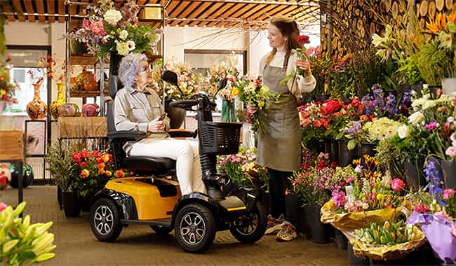 Dame sur un scooter électrique 4 roues Life Mobility Presto chez un fleuriste